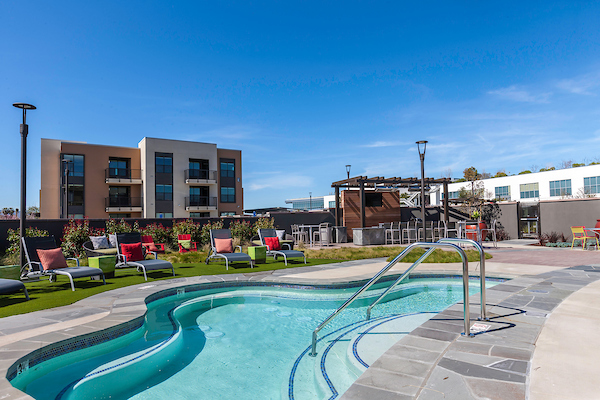 Outdoor spa surrounded by lounge seating and grass area.