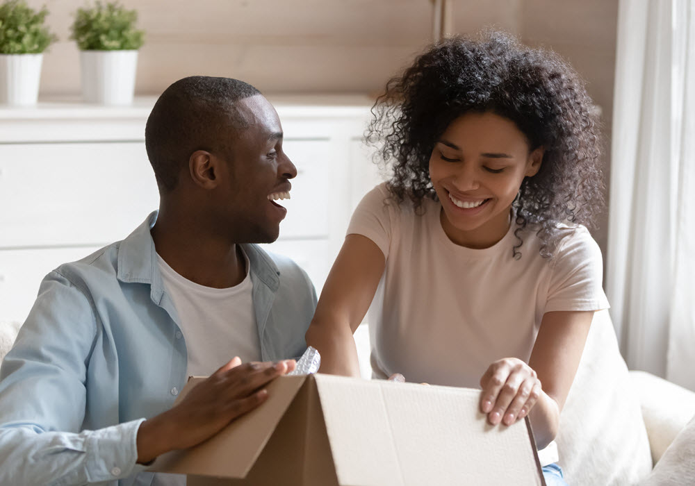 Smiling couple packing belongings in a moving box. 
