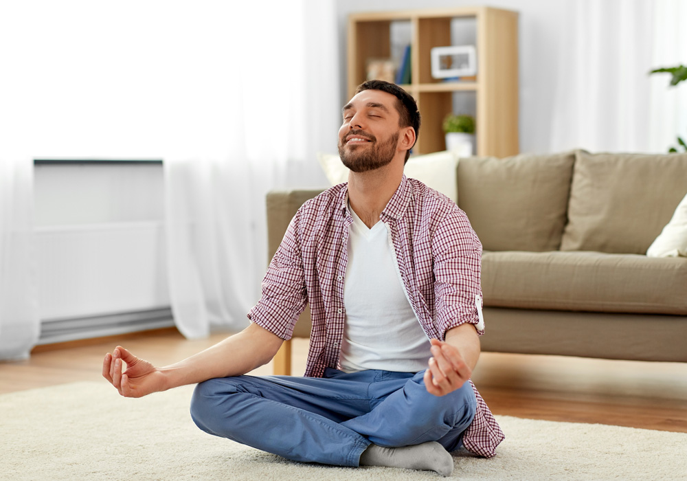 Man relaxed and meditating in his apartment living room 