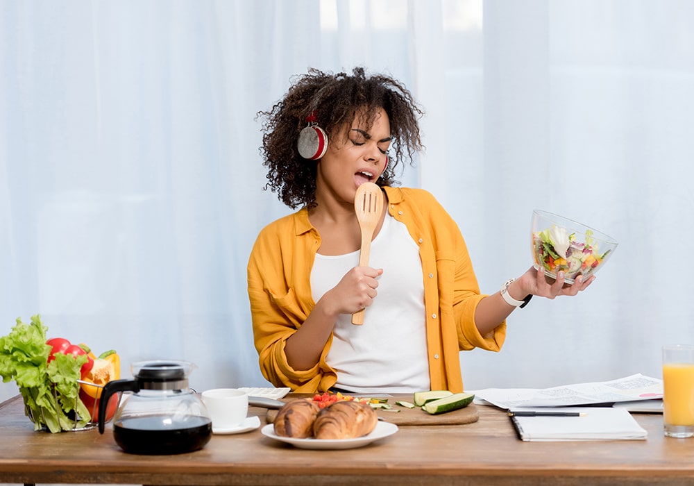 Happy woman cooking and listening to music in apartment kitchen