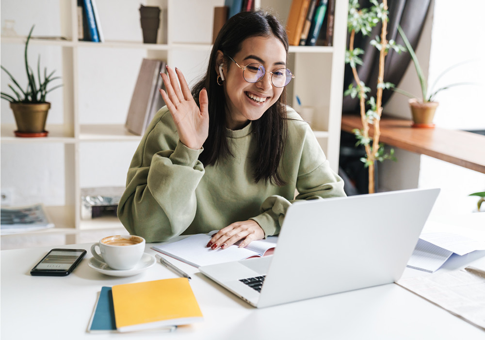Girl saying hello to class through her laptop