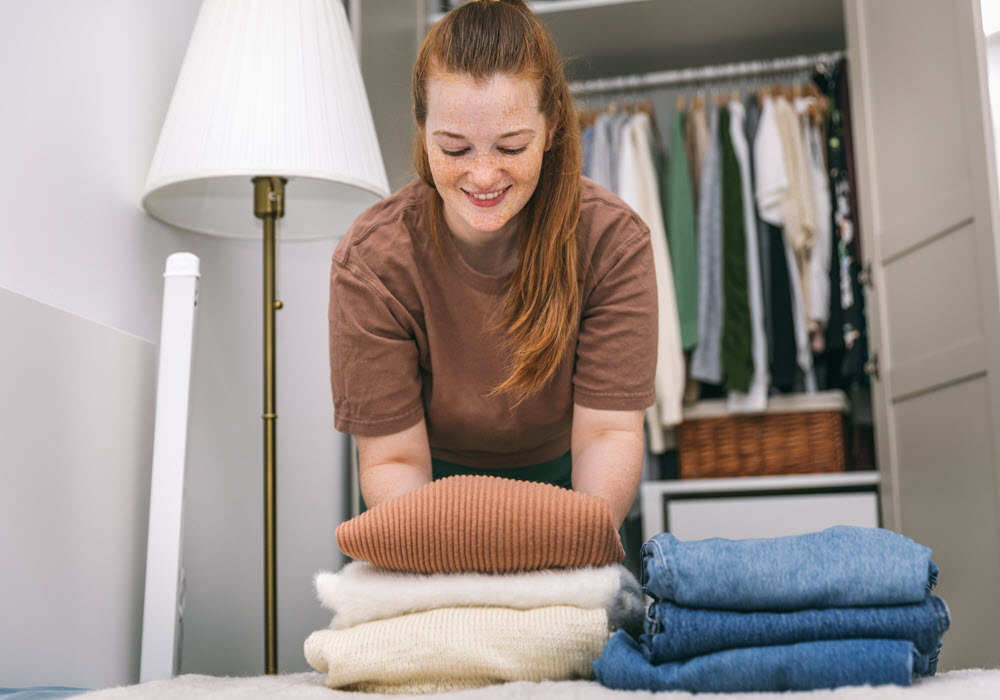 Woman folding and organizing clothes into closet.