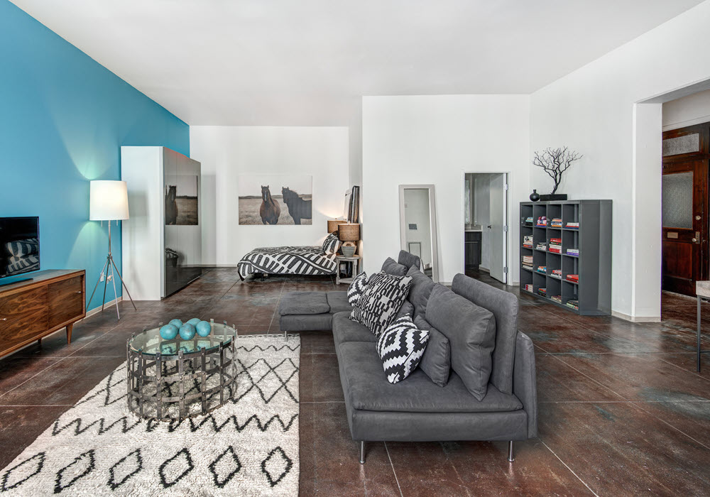 PE Lofts' staged studio apartment living area with lounge seating.