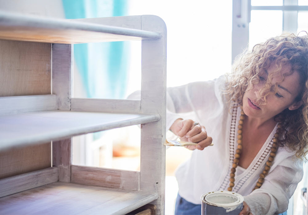 Woman adding color to her shelves with paint.