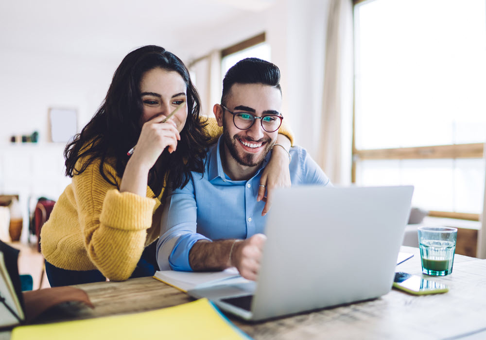 Man and woman looking at laptop screen in their apartment home.