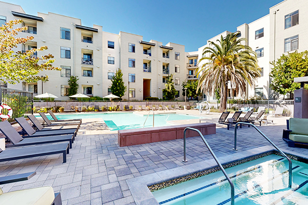 Outdoor spa and swimming pool with lounge chairs.