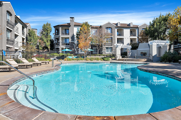 Outdoor swimming pool and spa surrounded by lounge chairs.