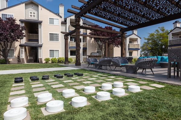BBQ area under pergola with lounge seating adjacent to lawn area with over-sized checkers.