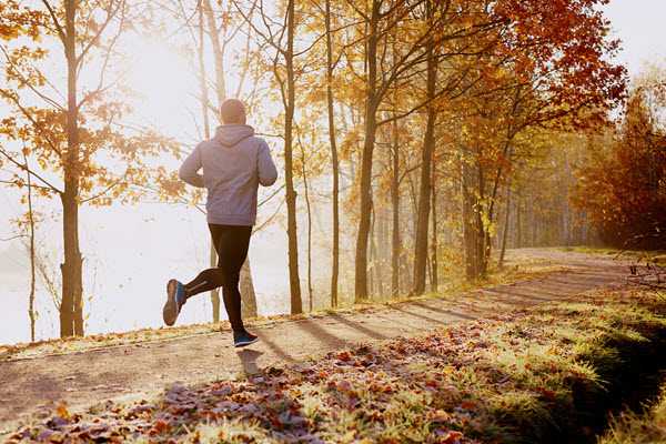 Man running on hiking trail at sunrise.