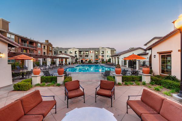 View of swimming pool area from community courtyard with lounge chairs.