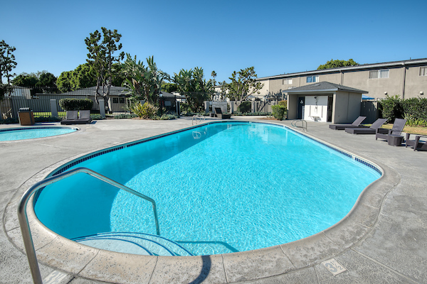 Outdoor swimming pool and spa surrounded by lounge chairs.